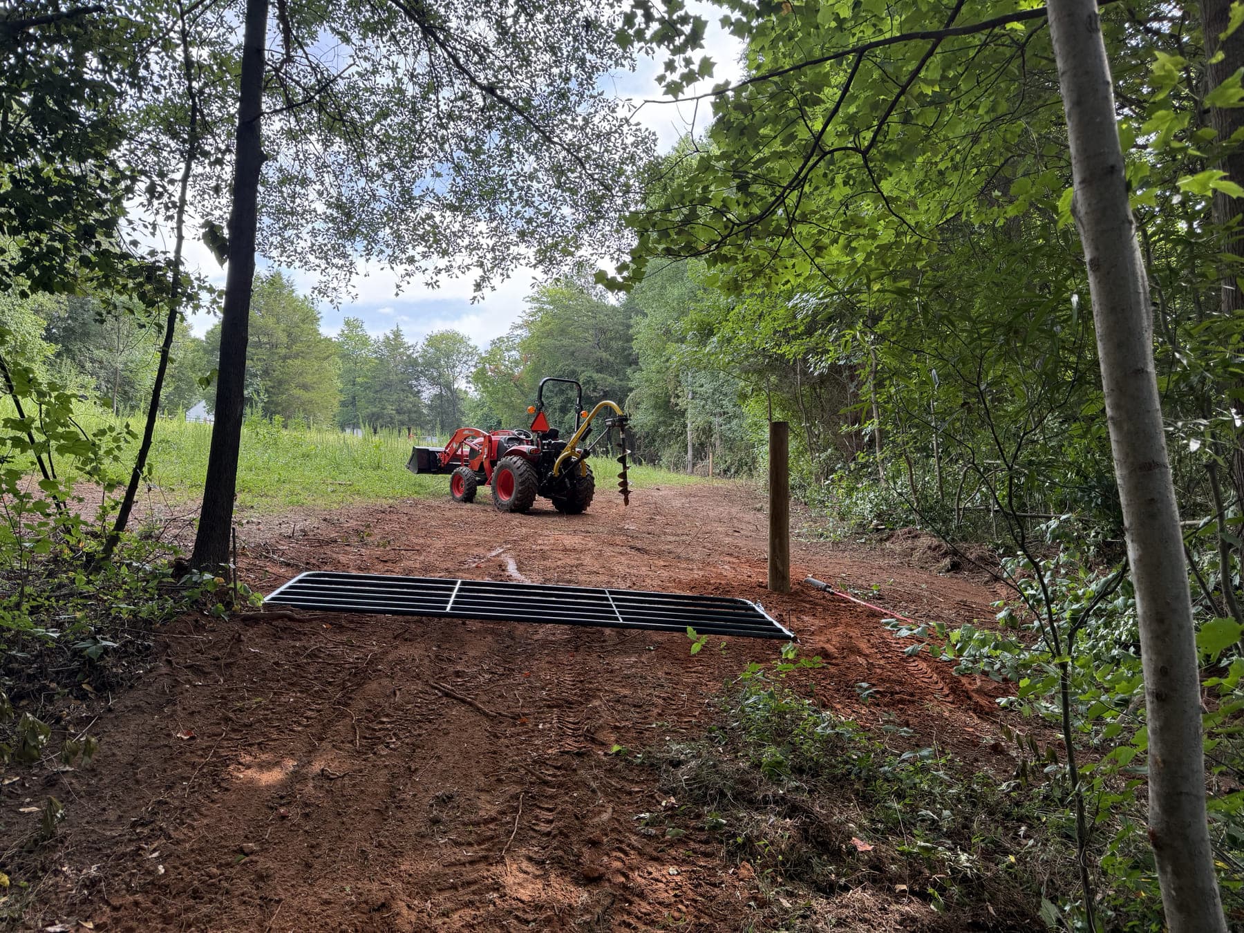 A cattle guard set into the dirt drive, tractor parked beyond it